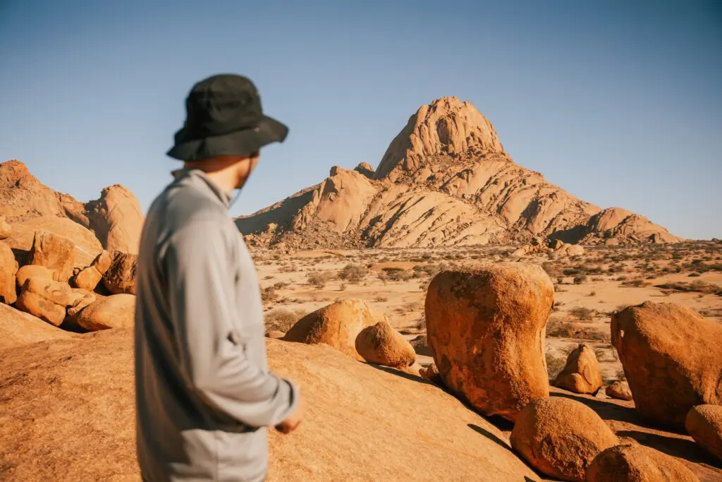 person in hat looking at Spitzkoppe mountain in Namibia