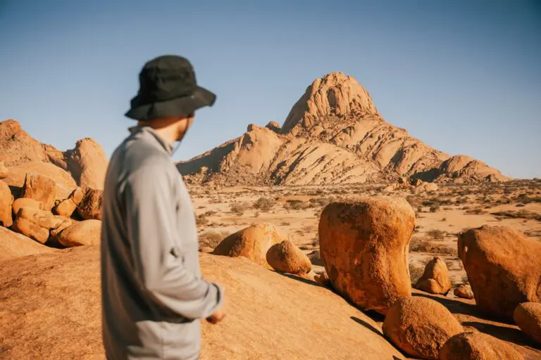 person in hat looking at Spitzkoppe mountain in Namibia
