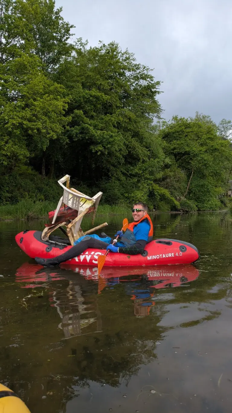 man in red inflatable boat with chair on river cleanup