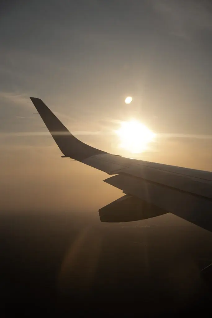 airplane wing at sunset from above the clouds