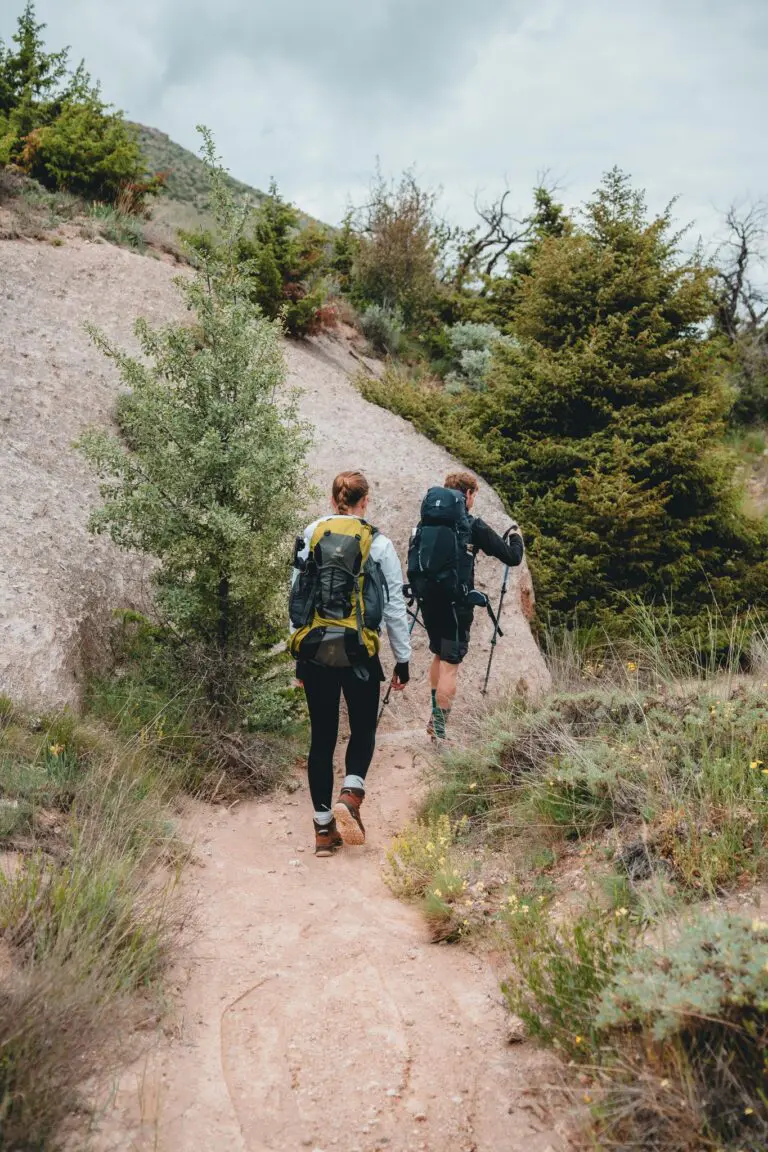 two hikers with backpacks and poles on a trail in Cappadocia