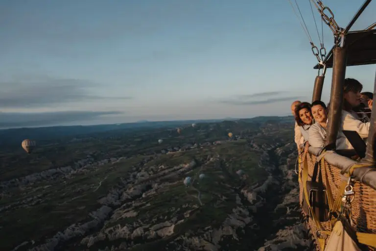 people in hot air balloon over Cappadocia landscape at sunrise
