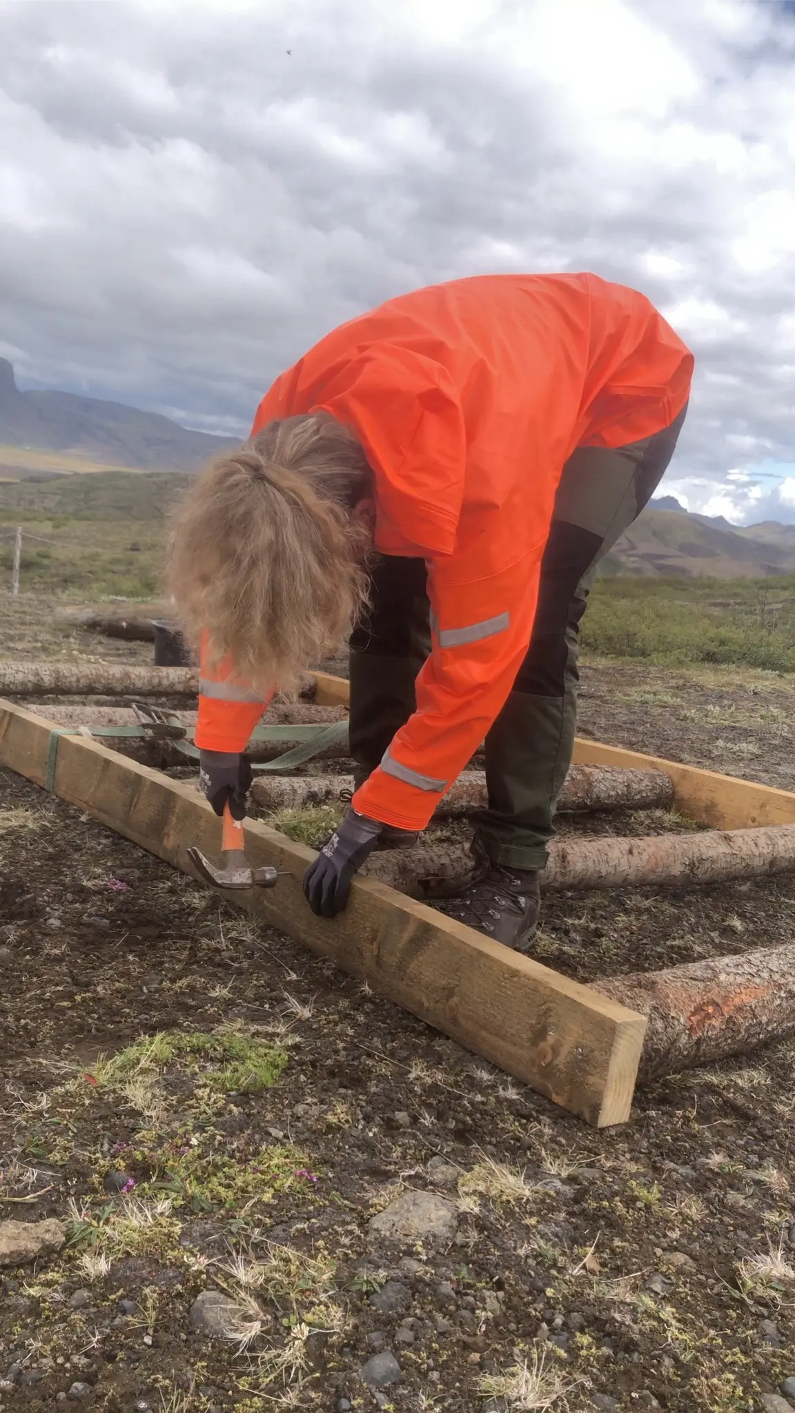 volunteer hammering wood in a rugged icelandic landscape