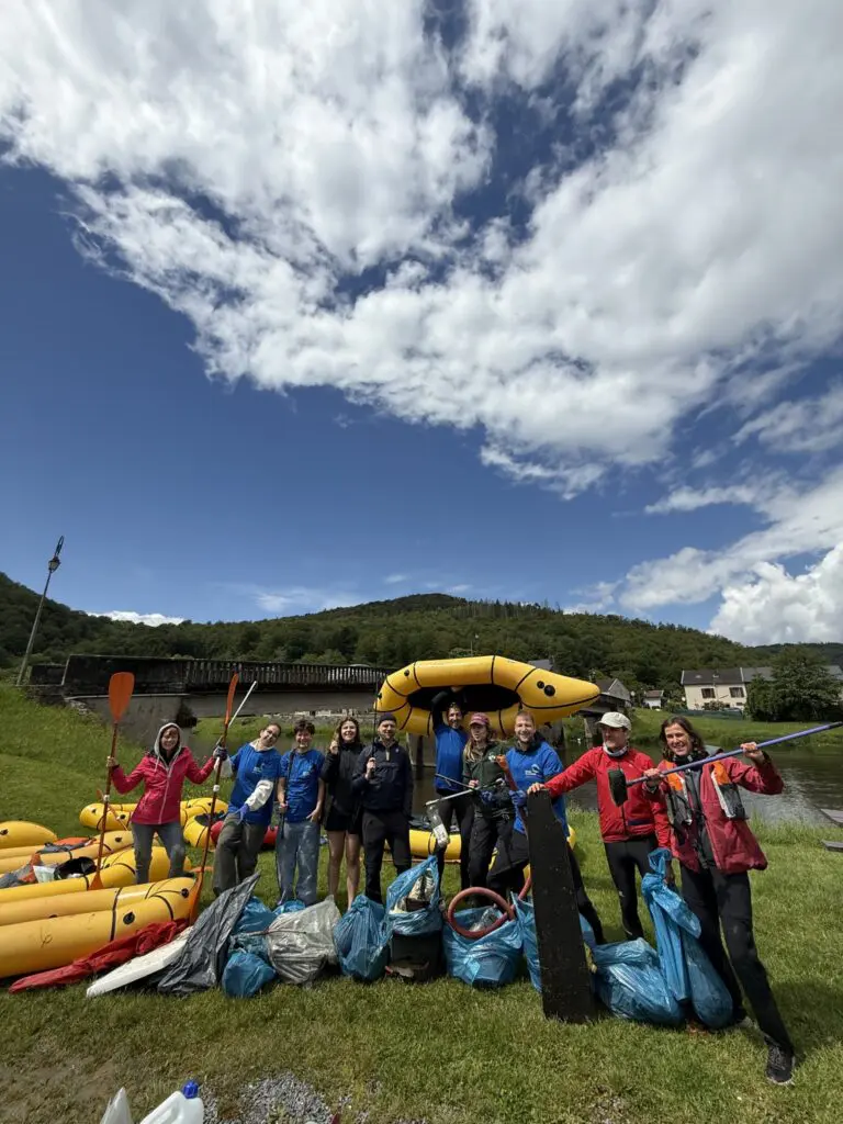 group of people with rafts and collected trash bags after river cleanup