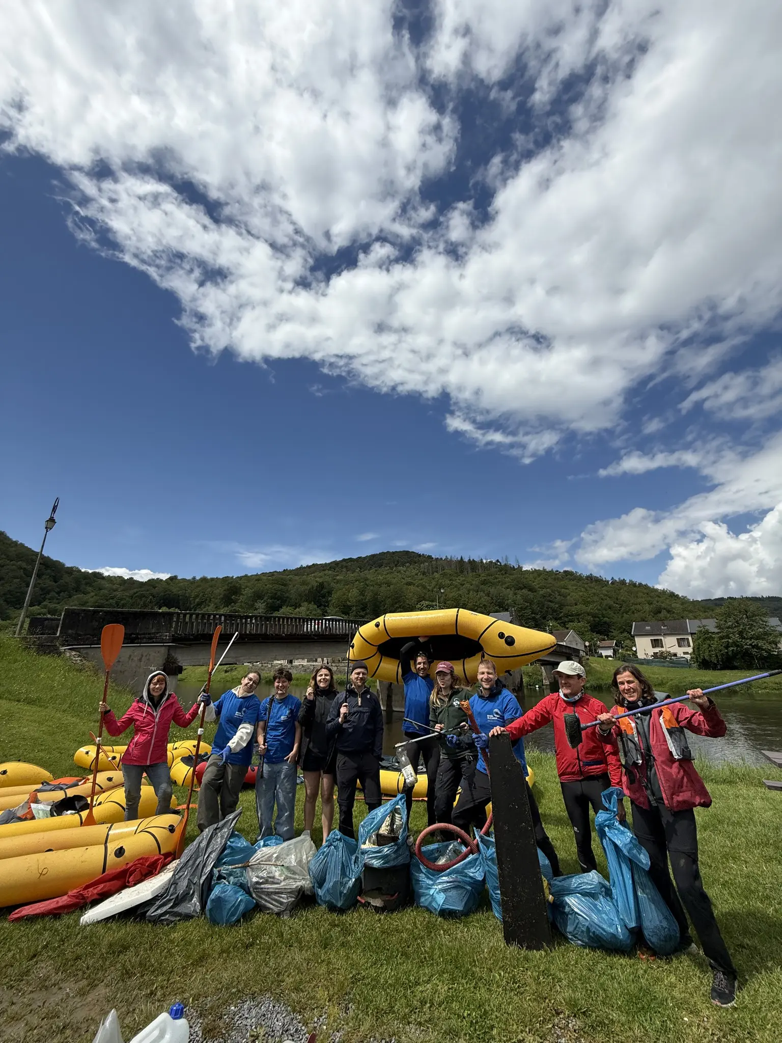 group of people with rafts and collected trash bags after river cleanup