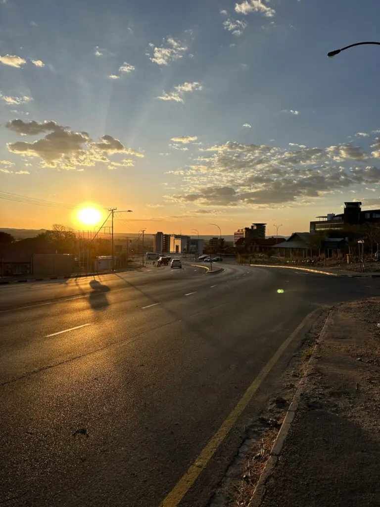 sunset over a city road with cars and buildings