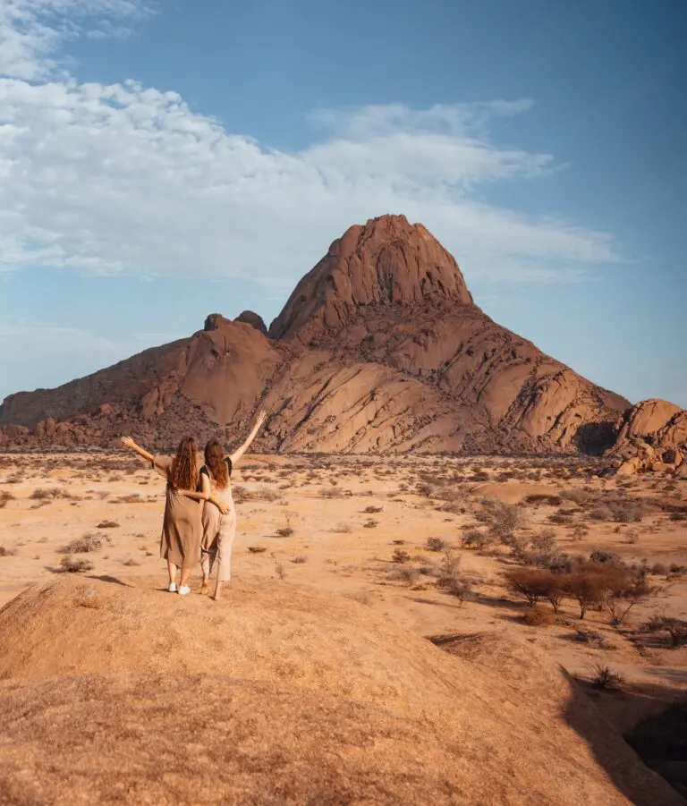 two women with arms raised admiring Spitzkoppe mountain Namibia