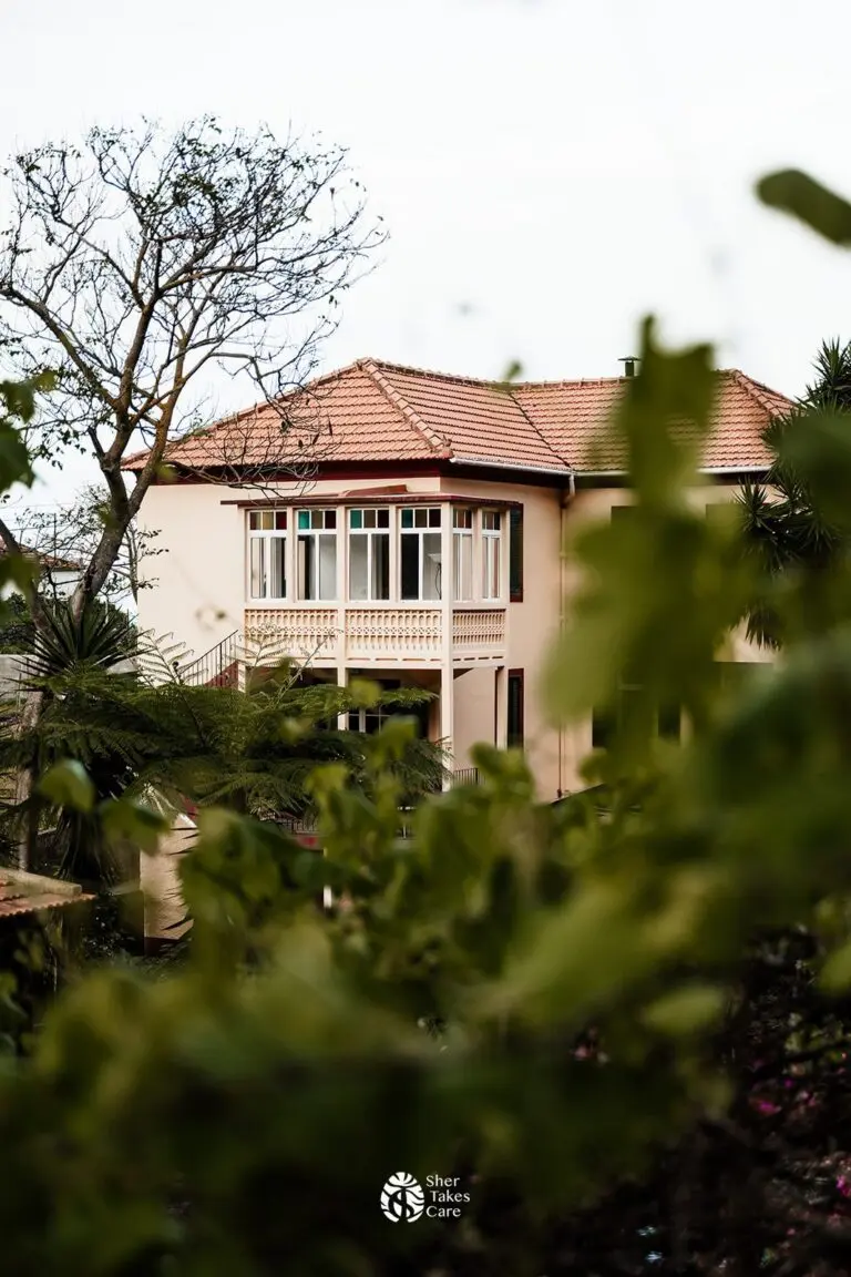 traditional house with terracotta roof and balcony surrounded by lush greenery
