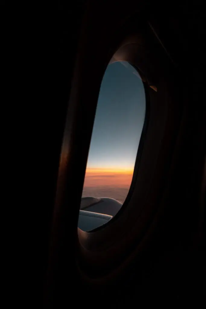 airplane window view of sunset over clouds