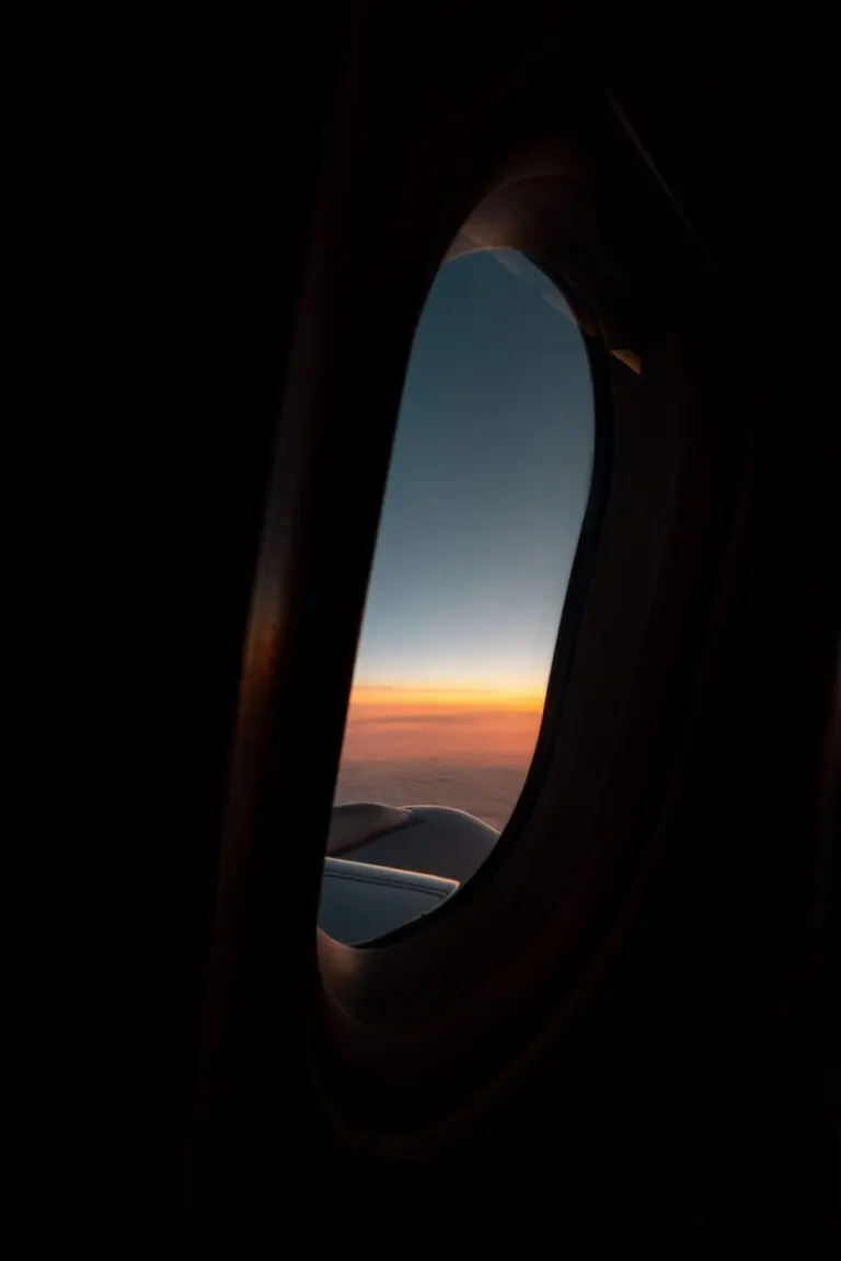 airplane window view of sunset over clouds