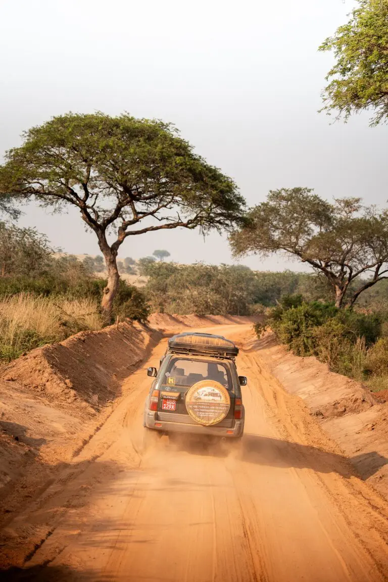 safari vehicle driving on a dusty road in Uganda
