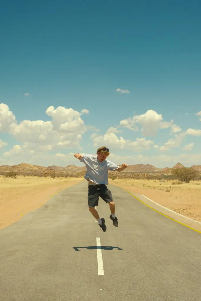 man jumping on desert road in Namibia