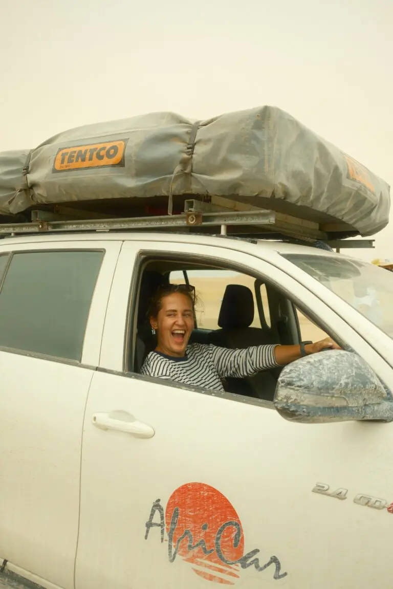 woman laughing in a white 4x4 with rooftop tent in Namibia