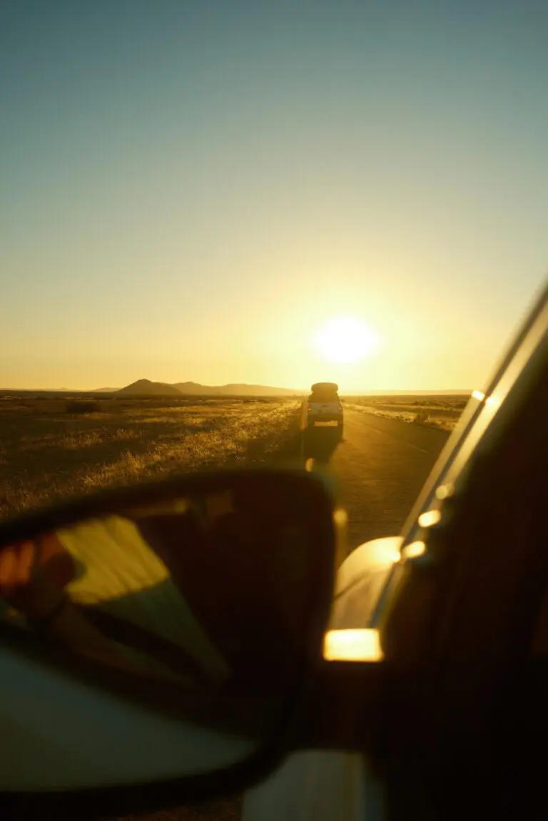 car driving on a desert road at sunset in Namibia