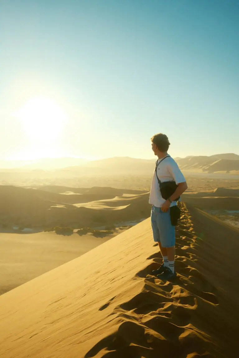 man standing on desert dune ridge at sunset in Namibia