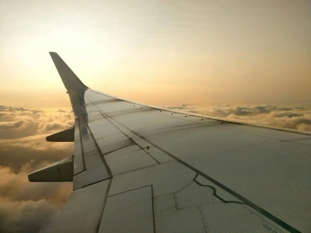 airplane wing above clouds at sunset