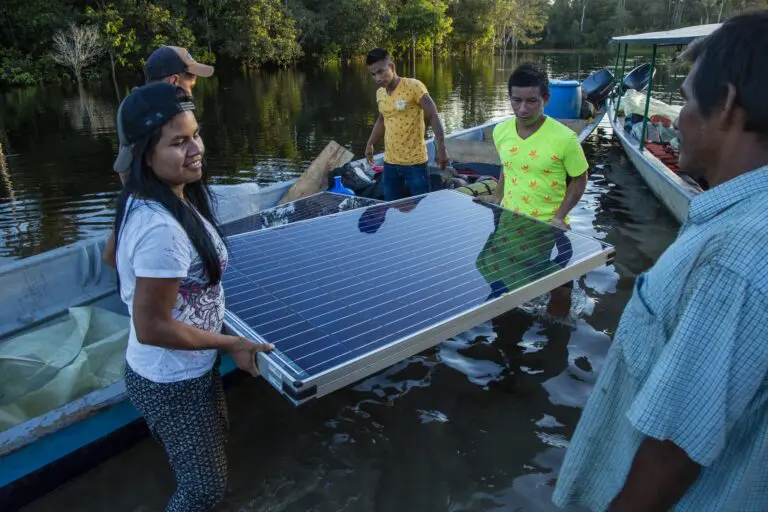 group of people carrying a solar panel in a river