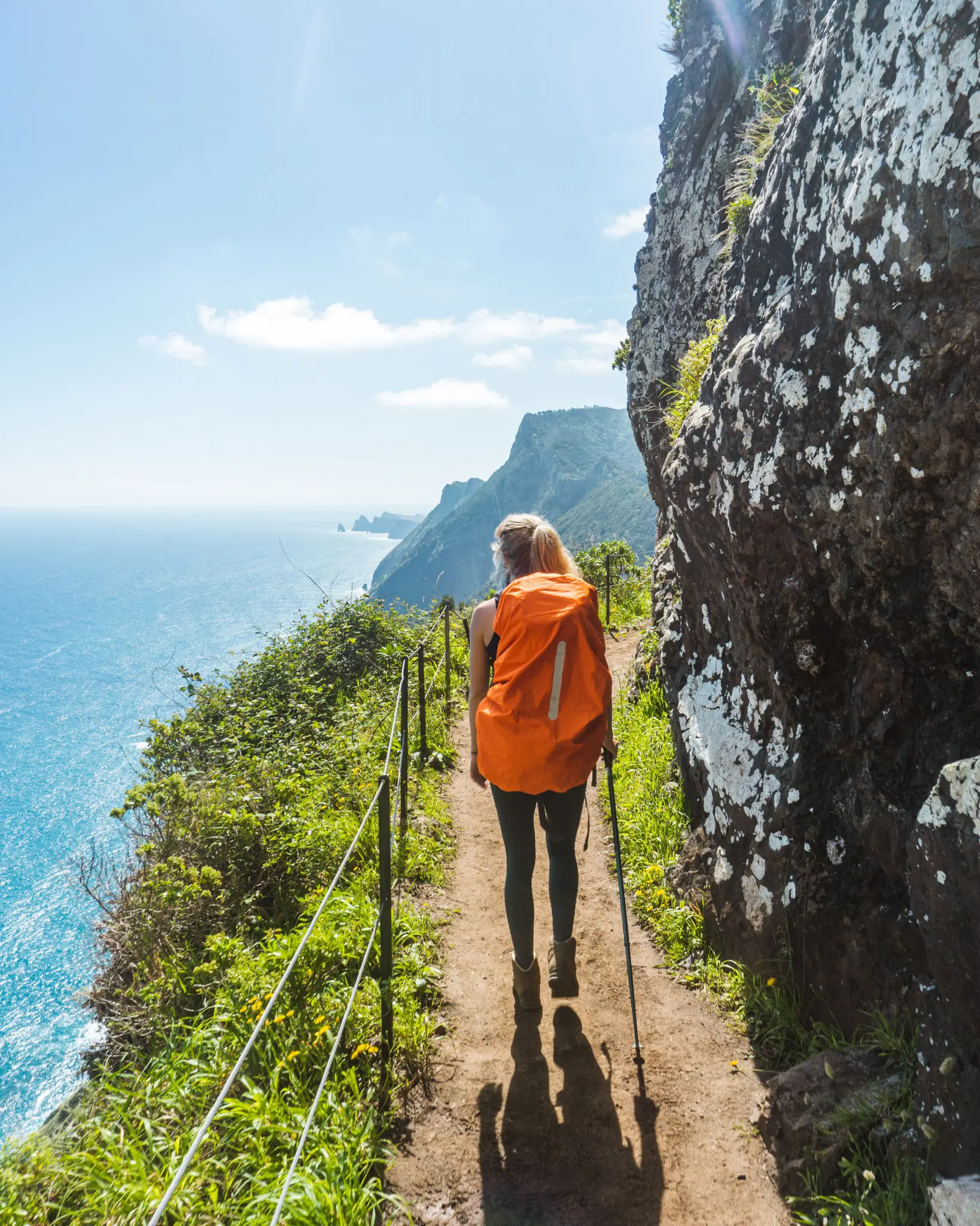 hiker with orange backpack on coastal trail in Madeira