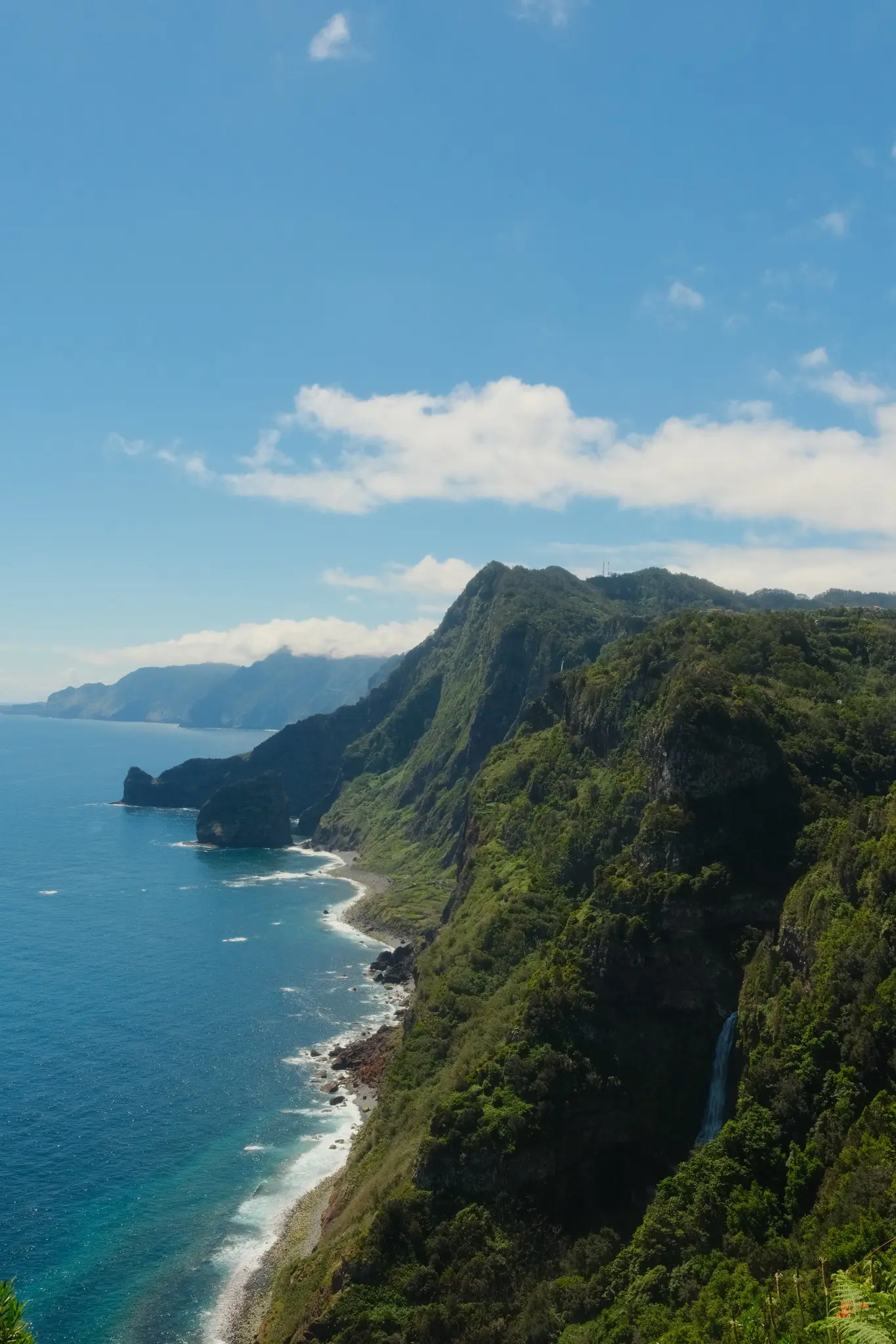 lush green cliffs and blue ocean with a waterfall in Madeira