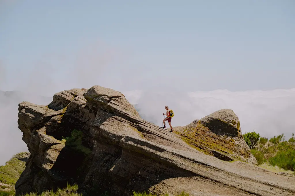 hiker on a rocky mountain ridge above clouds in Madeira