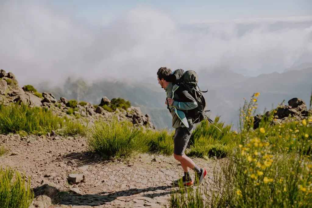 hiker with backpack on a mountain trail above the clouds